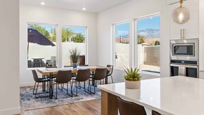 A modern kitchen with white cabinetry, a built-in microwave, and a large island.