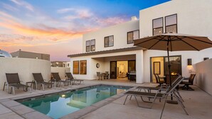 A modern house with a swimming pool, outdoor seating, and a patio area.