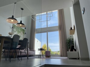 Enjoy a spacious living area with a dining table, sofa, and potted plant, offering a view of the outdoors.