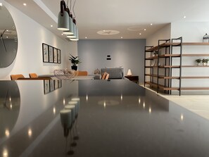 Relax in a contemporary living area with a sleek dining table, comfortable seating, and a large wall clock.