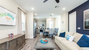 A modern living room with a beige sofa, a coffee table, and a dining area with a table and chairs.