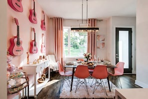 A dining area with pink chairs, a white table, and a chandelier. - Nashville family getaway: rooftop deck & Opry-themed karaoke room, sleeps 12 (Nashville)