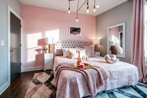 A bedroom with a large bed, bedside tables, a nightstand, a mirror, and a window with curtains.
