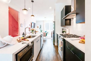 A modern kitchen with white countertops, stainless steel appliances, and pendant lighting. - Nashville family getaway: rooftop deck & Opry-themed karaoke room, sleeps 12 (Nashville)