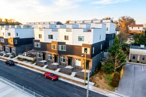 Un immeuble d’appartements moderne, doté d’un toit plat, de plusieurs logements et d’un espace de stationnement à l’avant.