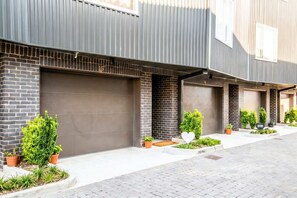 A modern building with multiple garage doors, potted plants, and a clean, paved walkway. - Grand Ole Opry-themed rooftop house | sleeps 16 near Centennial Park (Nashville)