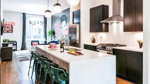 A modern kitchen with a central island, stainless steel appliances, and pendant lighting.