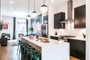 A modern kitchen with a central island, stainless steel appliances, and pendant lighting.