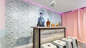 A bar area with a brick wall, a wooden bar counter, and three white stools.