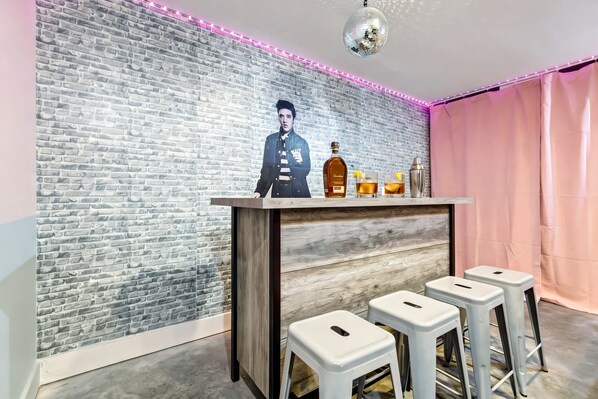 A bar area with a brick wall, a wooden bar counter, and three white stools.