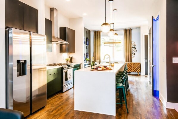 A modern kitchen with a central island, stainless steel appliances, and a dining area with chairs.