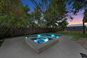 Tinaja rectangular con borde de piedra, rodeada por una valla de madera y árboles.
