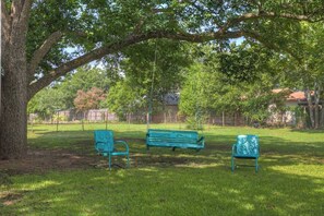 A park with a large tree, a swing set, and two benches.