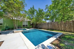 A rectangular swimming pool with a wooden deck and a green house in the background. - Clover Haus 2 Blks to Main/Pool & Hot-Tub! (Fredericksburg)