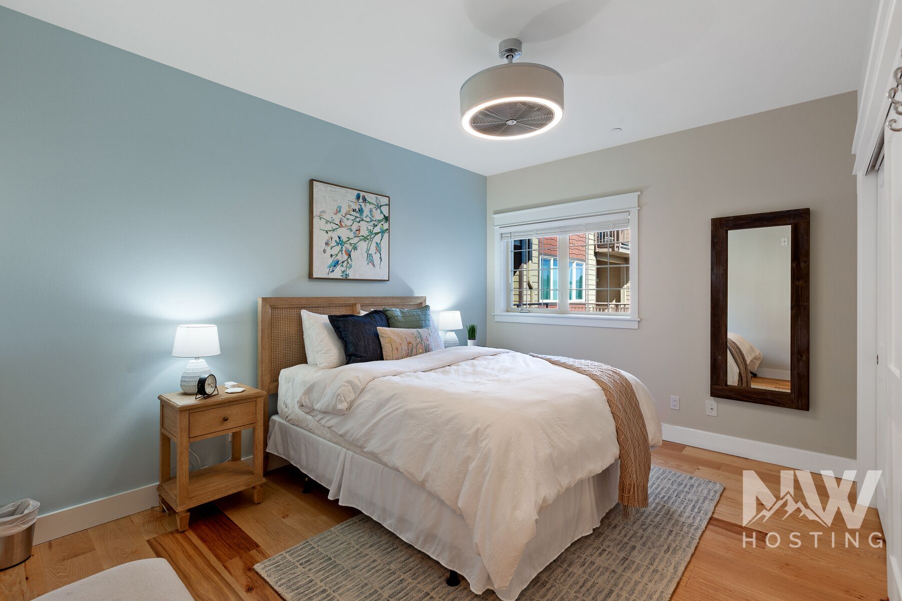A bedroom with a bed, bedside tables, a window, and a ceiling fan.