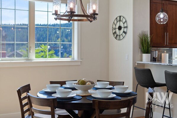 Un comedor con una mesa redonda dispuesta para cuatro personas, rodeada de sillas de madera. En el centro, un cuenco decorativo con flores.
