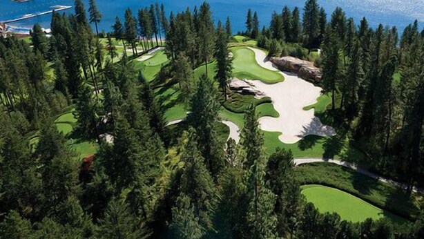Golfkenttä, jolta avautuu näkymä järvelle, ja jonka ympärillä on tiheää metsää.