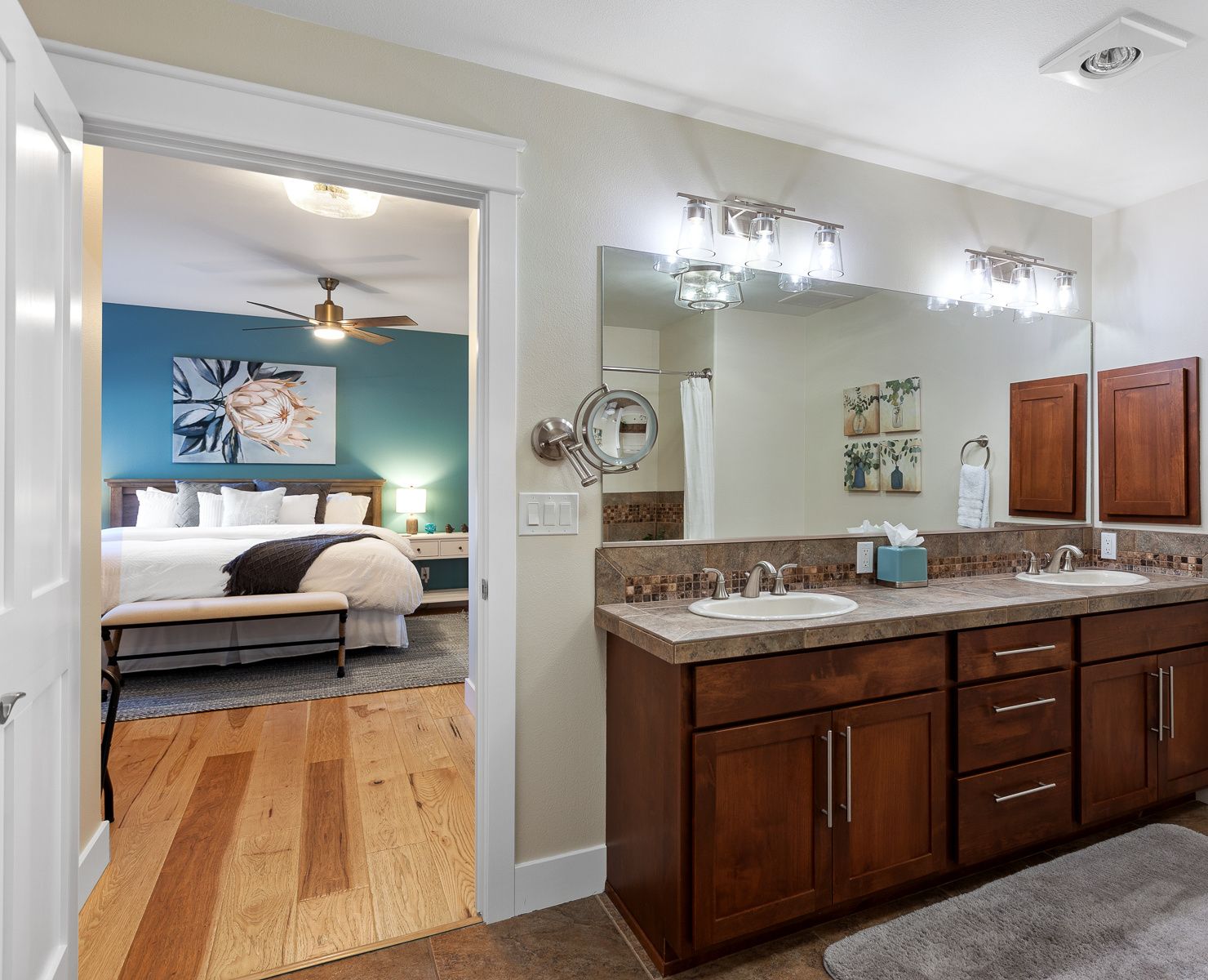A modern bathroom with a large vanity, a ceiling fan, and a shower area.