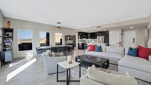 A spacious living room with a large sofa, a coffee table, and a dining area in the background.