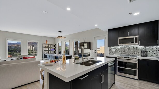 A modern kitchen with dark cabinets, a white countertop, and a large island.