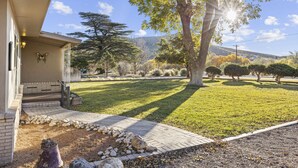 Une maison avec une allée dallée, une décoration en forme de papillon et une pelouse bien entretenue, agrémentée d’arbres et d’arbustes.