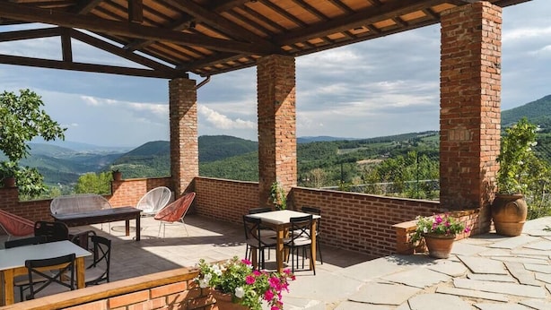An outdoor patio with brick columns, a table, chairs, and potted plants. - Le Fonti - Molino, chic and reserved (Pontassieve)