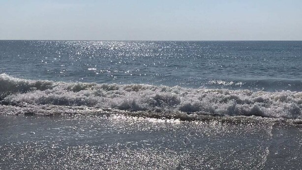 A beach with waves and a clear sky. - Coastal Cozy Condo: Pet Friendly! Steps to Beach, Perfect for Relaxing Getaways! (Carolina Beach)
