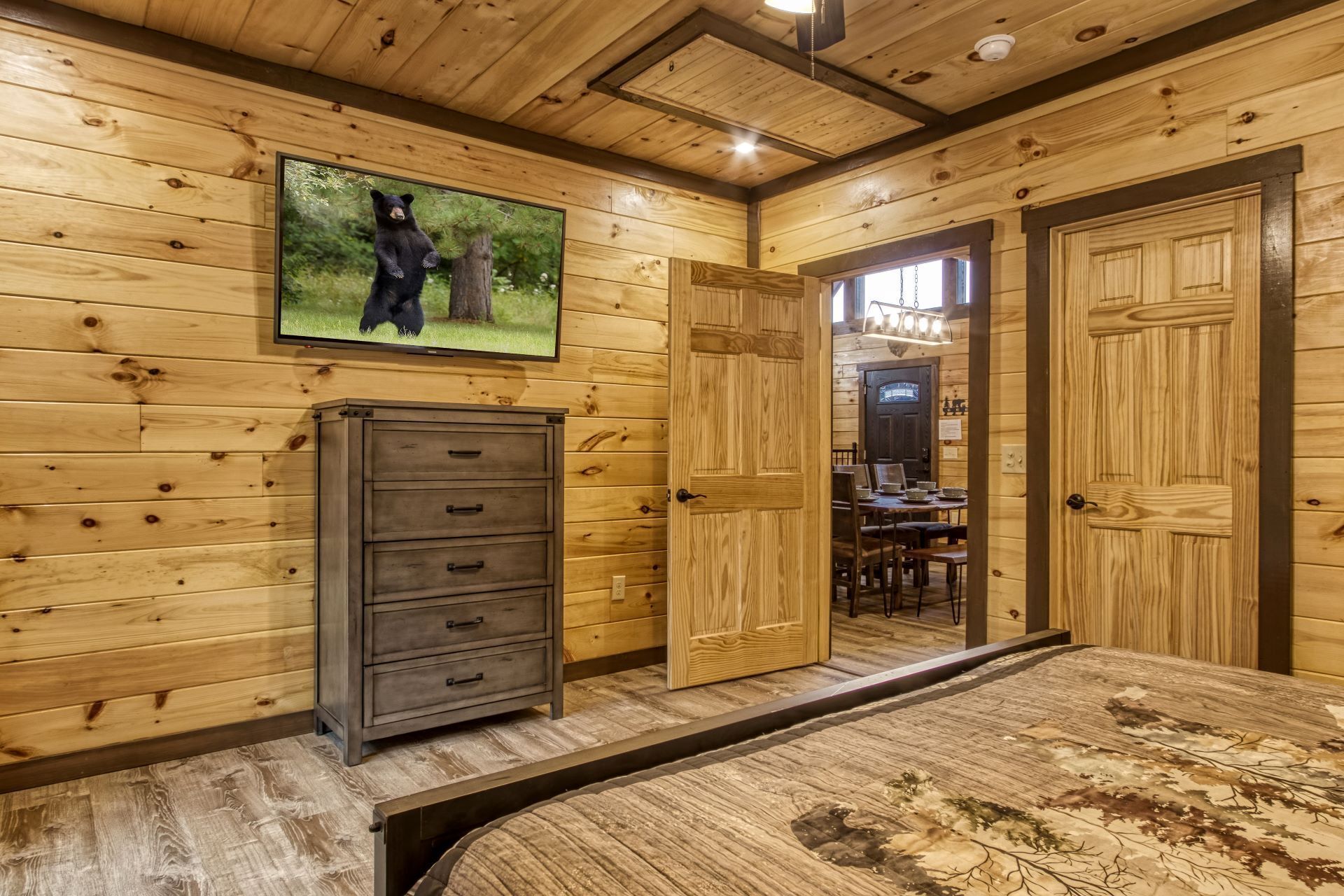 A wooden-paneled room with a bed, a dresser, and a television mounted on the wall.