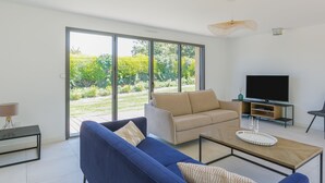 Ett modernt vardagsrum med en blå soffa, en beige soffa och en tv-apparat placerad på ett träbord.