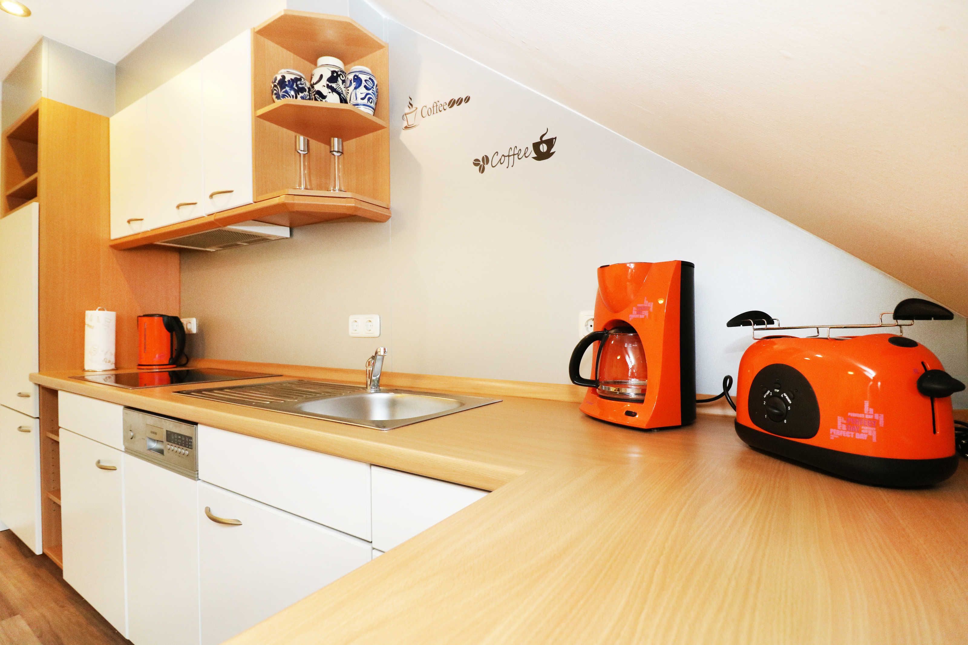 Eine kleine Küche mit weißen Schränken, einer Holz Arbeitsplatte, einer Kaffeemaschine und einem Toaster.
