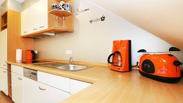 Eine kleine Küche mit weißen Schränken, einer Holz Arbeitsplatte, einer Kaffeemaschine und einem Toaster.