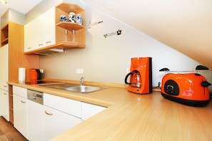 Eine kleine Küche mit weißen Schränken, einer Holz Arbeitsplatte, einer Kaffeemaschine und einem Toaster.
