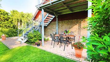 Eine Terrasse mit Ziegelmauer, einer Metalltreppe und einem Tisch mit Stühlen.
