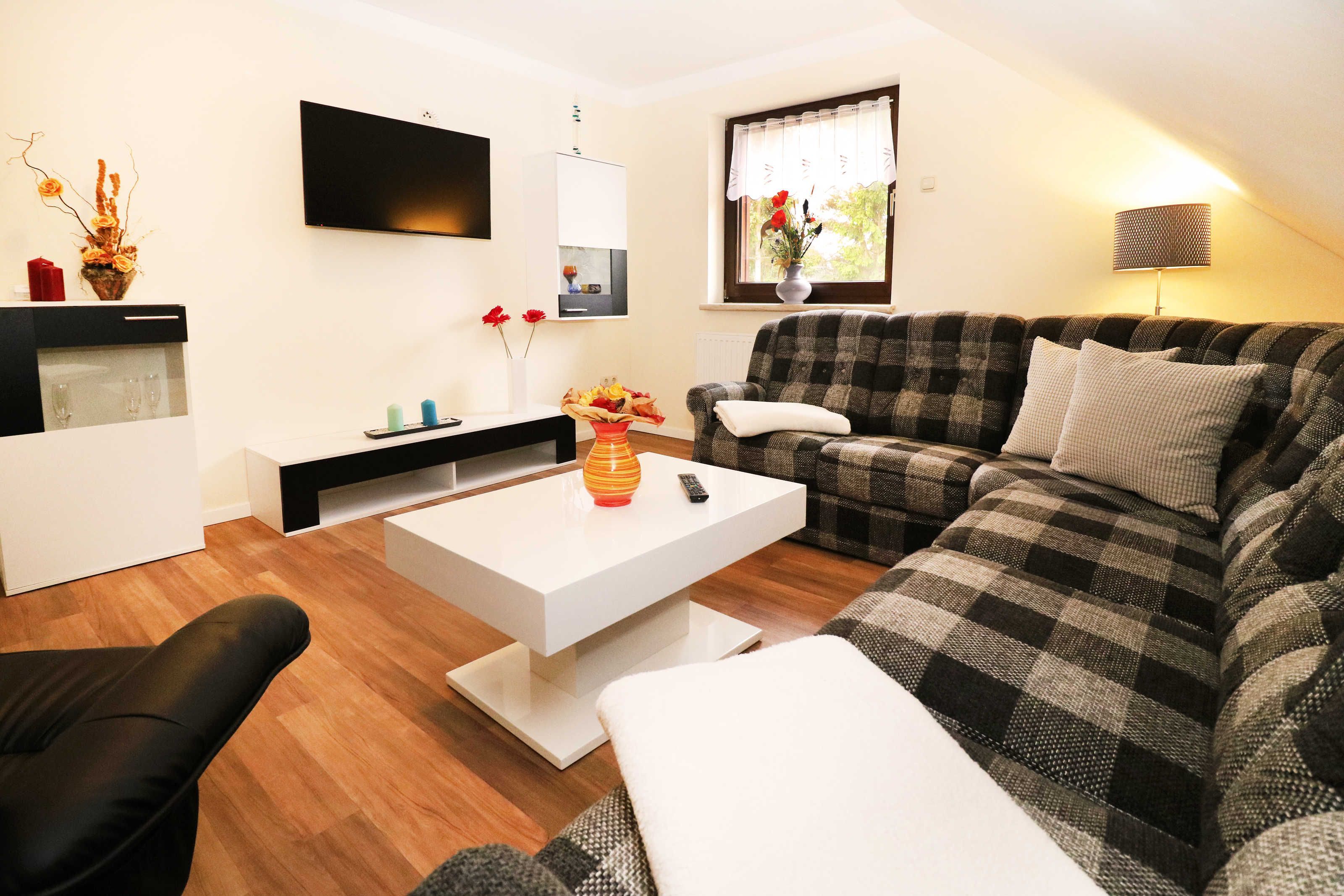 A modern living room with a checkered sofa, a white coffee table, and a black armchair.