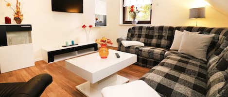 A modern living room with a checkered sofa, a white coffee table, and a black armchair.