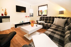 A modern living room with a checkered sofa, a white coffee table, and a black armchair. - Wolfgram Apartment with Balcony - Ferienwohnung Wolfgram (Trassenheide)