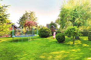 A well-maintained garden with a trampoline, a slide, and various trees and bushes. - Wolfgram Apartment with Balcony - Ferienwohnung Wolfgram (Trassenheide)