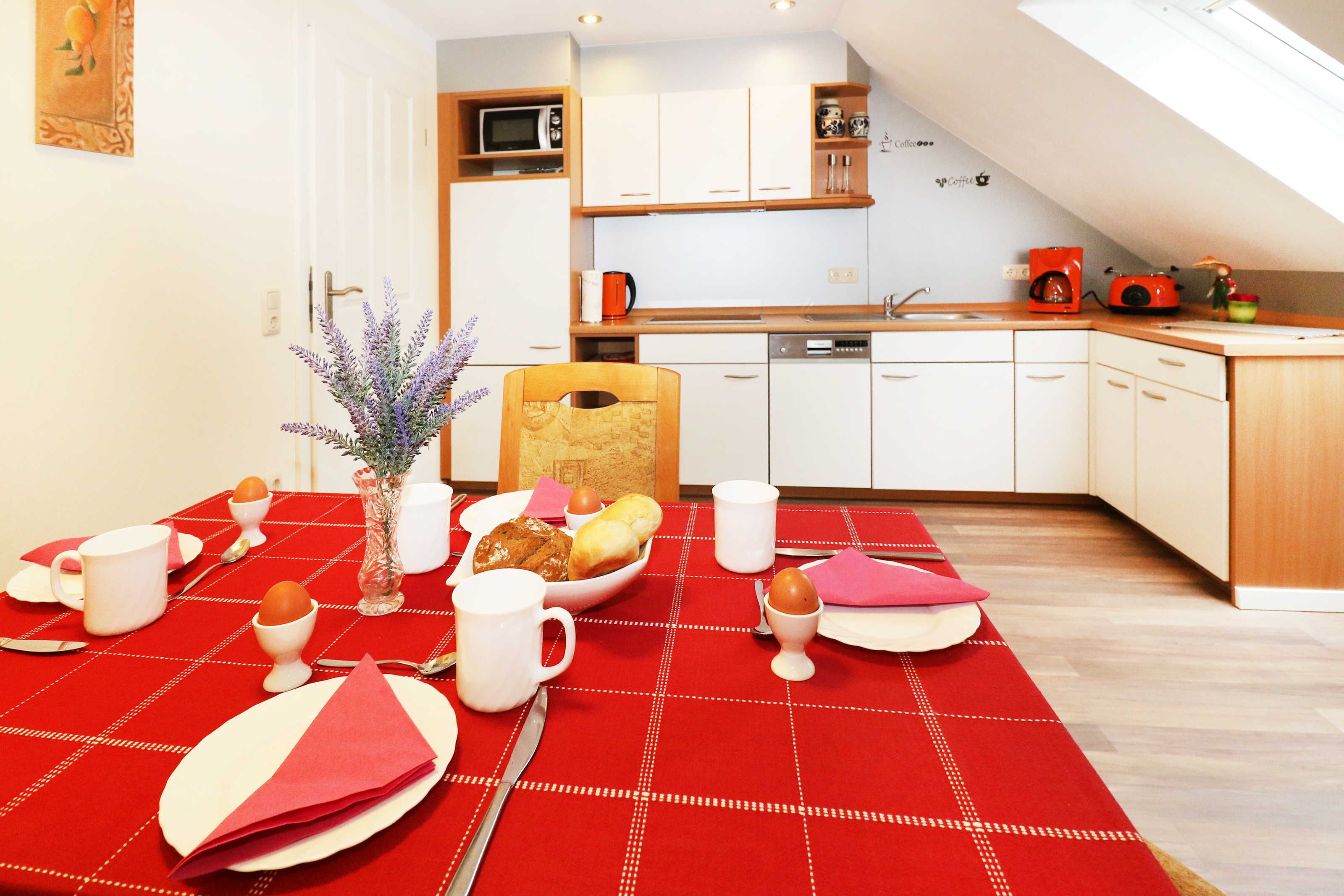 Eine moderne Küche mit weißen Schränken, einer Holz Arbeitsplatte und einer rotkarierten Tischdecke.