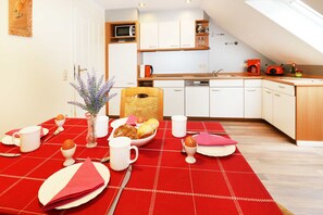 Una cocina moderna con armarios blancos, una encimera de madera y un mantel a cuadros rojos.