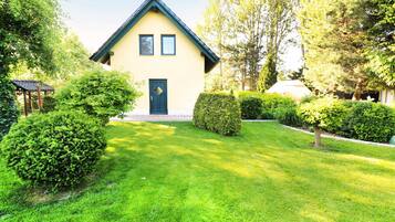 Ein zweistöckiges Haus mit dunkelblauem Dach und einer gelben Fassade, umgeben von gepflegten Rasenflächen und Hecken.