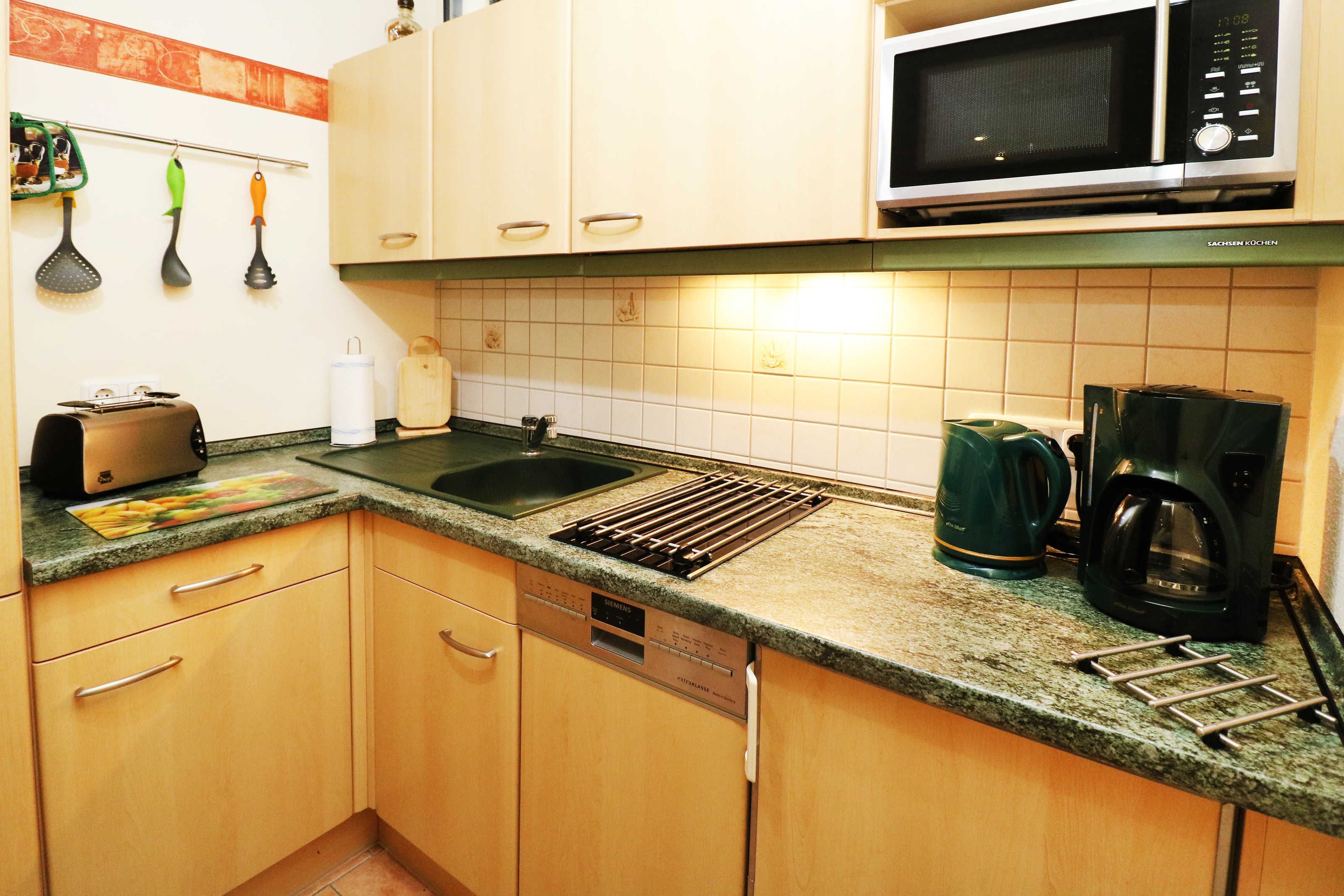A kitchen with wooden cabinets, a microwave, a toaster, a kettle, and a coffee maker.