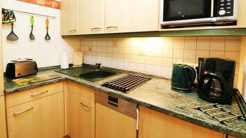 A kitchen with wooden cabinets, a microwave, a toaster, a kettle, and a coffee maker.