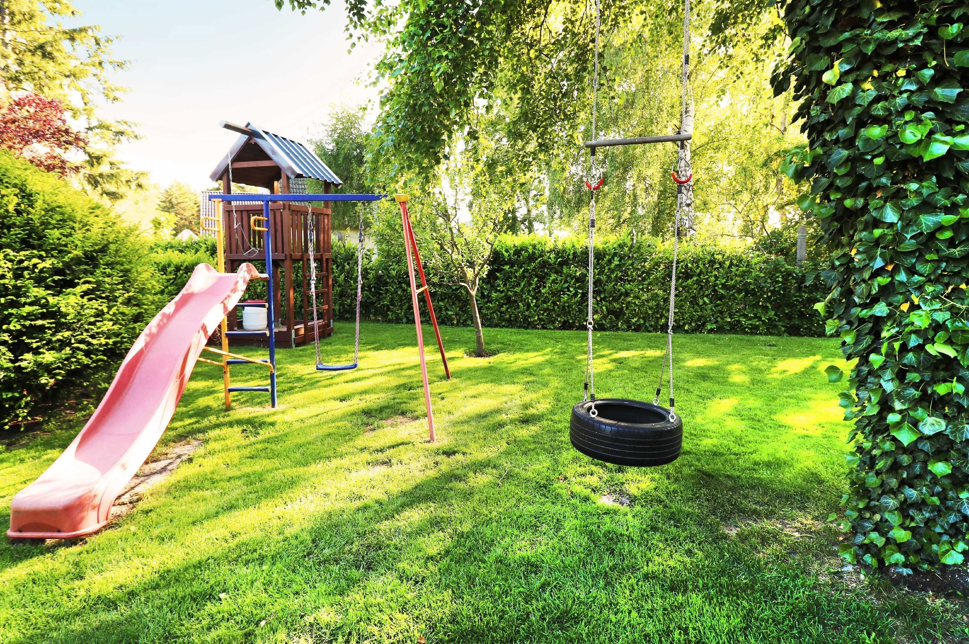 Ein Spielplatz mit Rutsche, Schaukeln und einer Kette mit Reifen.