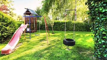 Ein Spielplatz mit Rutsche, Schaukeln und einer Kette mit Reifen.