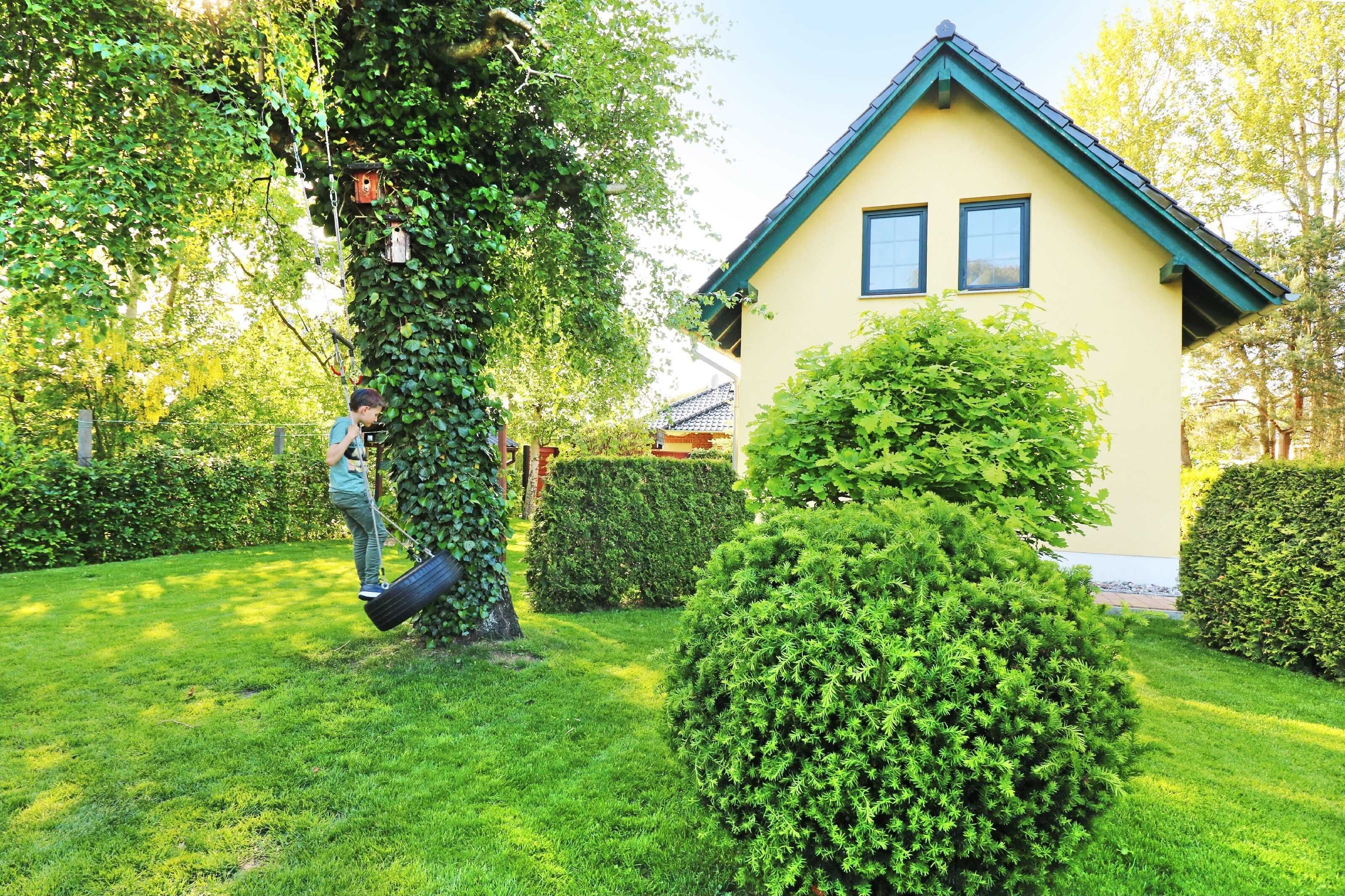 Ein Haus mit einem grünen Dach und einem gepflegten Garten.