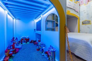 Une salle de jeux pour enfants avec un plafond éclairé en bleu, un lit superposé et divers jouets.