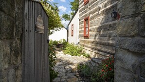 A stone pathway leading to a wooden cottage with a sign reading "Welcome to Wildflower Cottage." - Wildflower Cottage/PERFECT LOCATION!!/Walk to Main/Marktplatz!! (Fredericksburg)