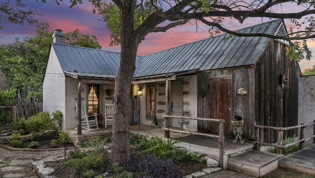 A rustic building with a metal roof, a wooden porch, and a stone pathway leading to the entrance. - Wildflower Cottage/PERFECT LOCATION!!/Walk to Main/Marktplatz!! (Fredericksburg)