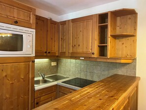 A kitchen with wooden cabinets, a microwave, a sink, and a countertop.