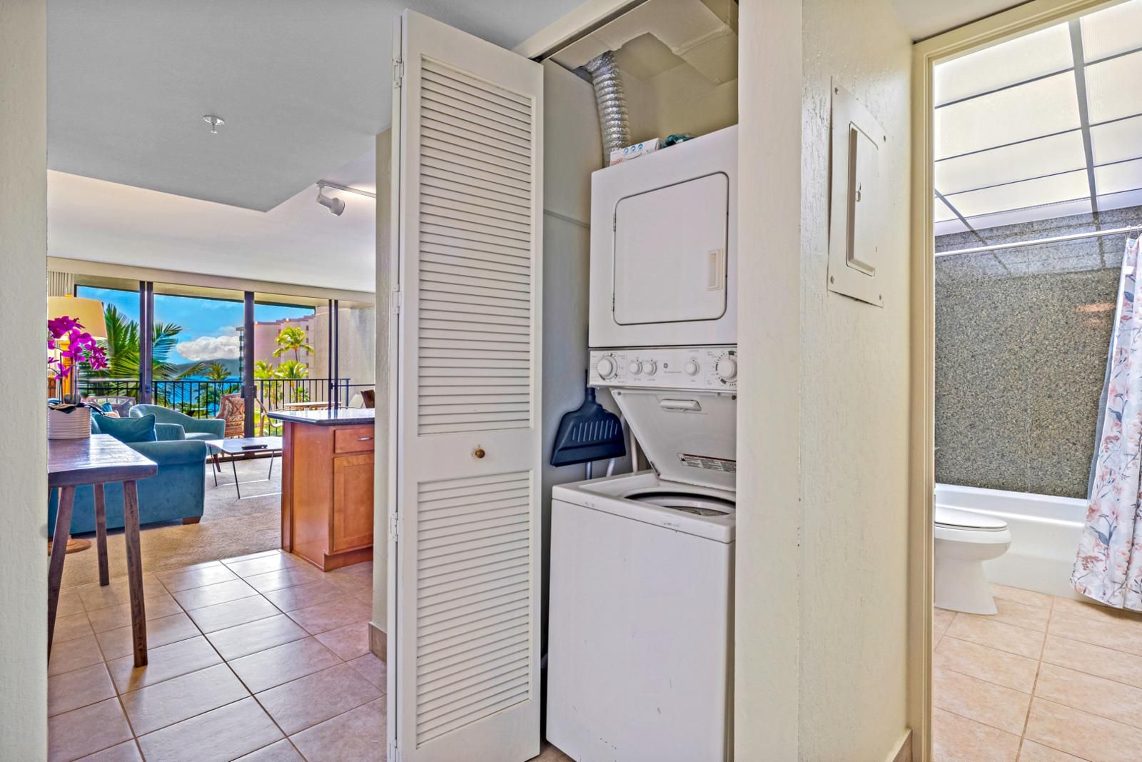 Un espace de vie compact comprenant un coin buanderie, une petite kitchenette et un balcon avec vue sur l’océan.